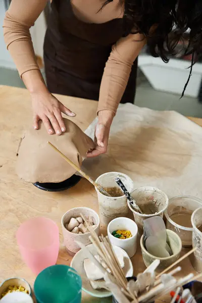 Young woman in apron making pottery in well lit studio. — Stock Photo