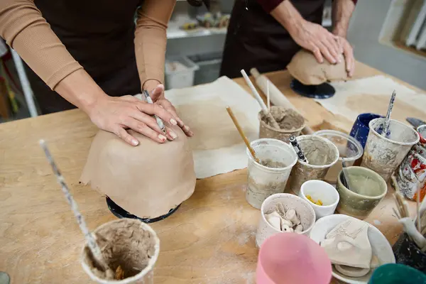 A couple forms pottery while surrounded by creative tools and materials. — Stock Photo