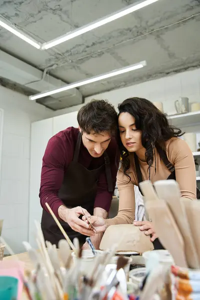 A couple collaborates lovingly to shape pottery in a modern workspace. — Stock Photo