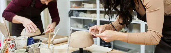Una pareja forma apasionadamente la arcilla juntos, disfrutando del arte de la cerámica. - foto de stock