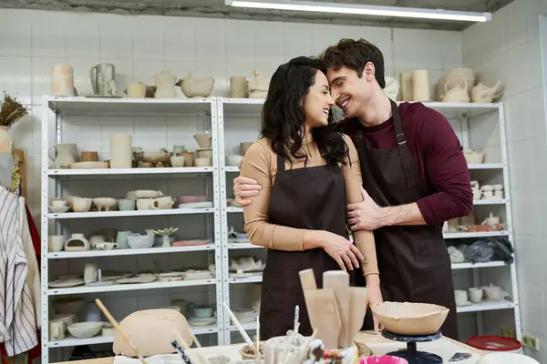 A joyful couple shares a moment while shaping clay in an artistic space. — Stock Photo