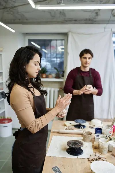 Un couple moule joyeusement de l'argile, partageant sa créativité dans un atelier de poterie contemporain. — Photo de stock