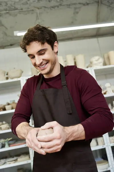 Joyeux bel homme dans le tablier faire de la poterie en studio. — Photo de stock