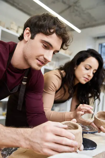 A loving couple enjoys molding clay in a contemporary pottery studio. — Stock Photo