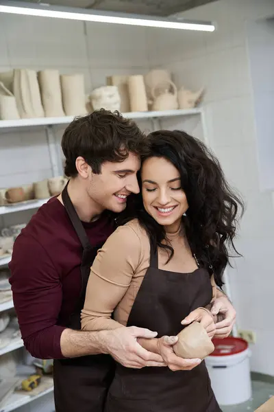 Una pareja abraza mientras hace cerámica en un estudio luminoso. - foto de stock