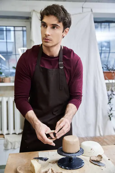 Good looking male in apron making some pottery in studio. — Stock Photo