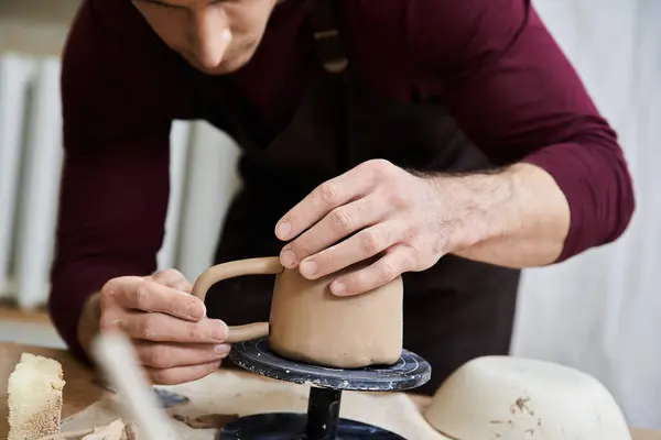Young man in black apron making pottery with his hands. — Stock Photo