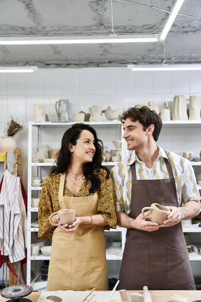 A couple shares smiles while shaping clay in a bright pottery studio. — Stock Photo