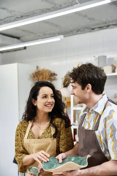 A loving couple shares smiles while shaping clay in a vibrant studio. — Stock Photo