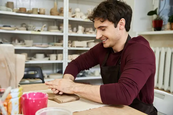 Cheerful man at table making pottery. — Stock Photo