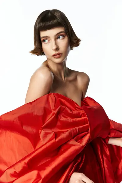 A young woman showcases elegance in a vibrant red dress with a dramatic bow. — Stock Photo