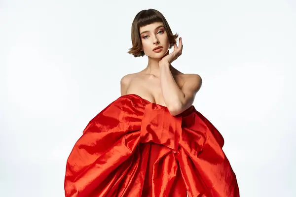 A fashionable young woman poses gracefully in a vibrant red dress. — Stock Photo