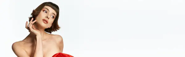 A stylish woman with short hair showcases her red dress in a striking pose. — Stock Photo