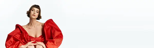 A young woman with short hair showcases her fashion in a vibrant red dress. — Stock Photo