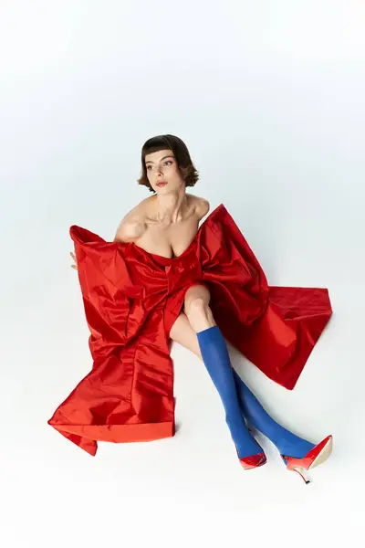 A graceful young woman showcases her vibrant red dress and striking blue footwear. — Stock Photo