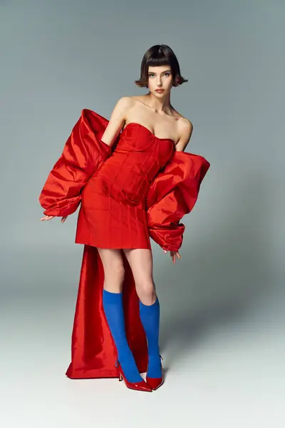 A confident young woman showcases her unique fashion sense in a vibrant red outfit. — Stock Photo