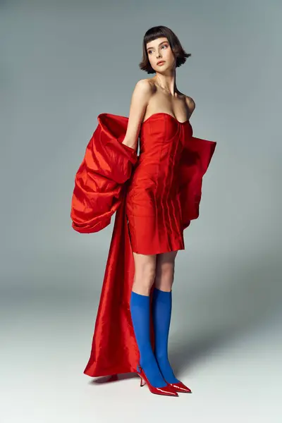 A young woman showcases a bold red dress with oversized bow details. — Stock Photo
