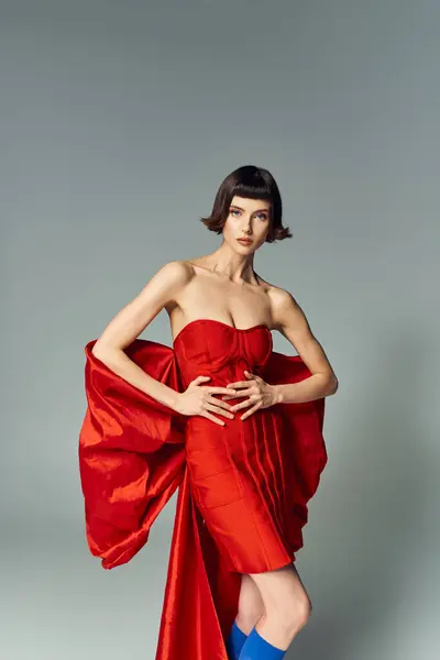 Une femme élégante pose avec confiance dans une robe rouge vibrante avec un arc audacieux. — Photo de stock