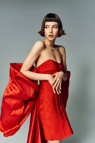 Uma mulher mostra um vestido vermelho vibrante, destacando criatividade e elegância. — Fotografia de Stock