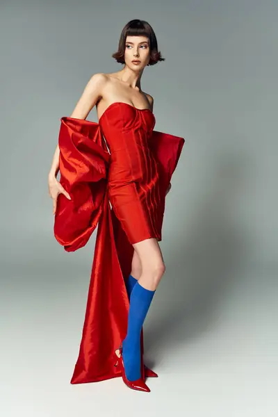 A beautiful woman showcases a bold red dress, embodying elegance and creativity. — Stock Photo