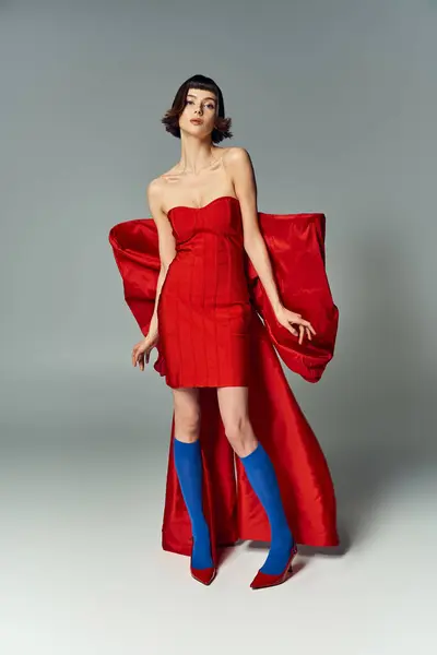 Une femme élégante présente sa robe rouge vibrante avec un arc surdimensionné dans une position chic. — Photo de stock