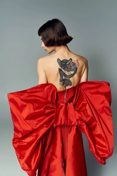 A fashionable woman turns, highlighting her unique dress and captivating tattoo. — Stock Photo