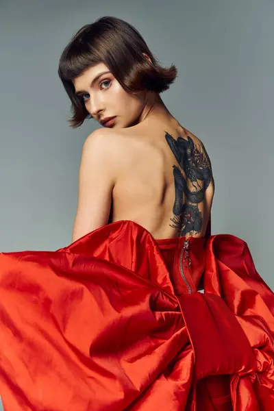 A young woman showcases elegance in a vibrant red dress with a large bow. — Stock Photo