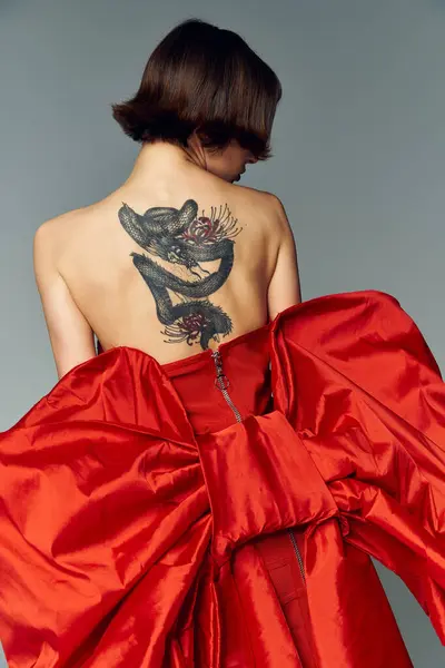 A stylish figure in a vibrant red dress displays intricate body art on her back. — Stock Photo