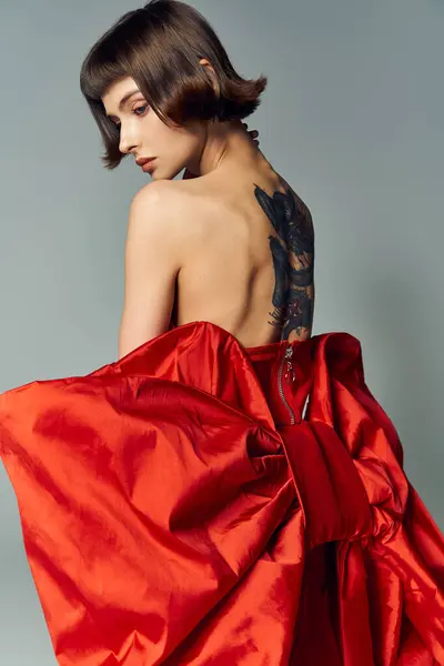 Uma jovem mulher elegante posa graciosamente em um vestido vermelho ousado. — Stock Photo