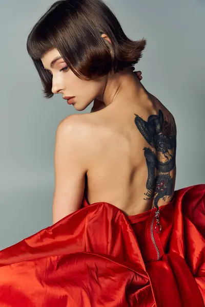 A young woman showcases elegance in a dramatic red dress with exquisite detailing. — Stock Photo
