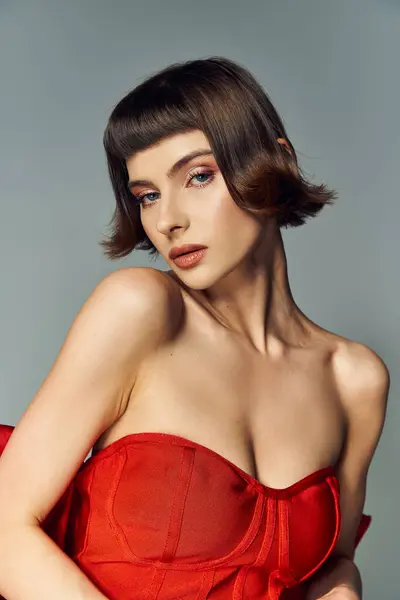 A stylish young woman showcases beauty in a vibrant red dress with a big bow. — Stock Photo