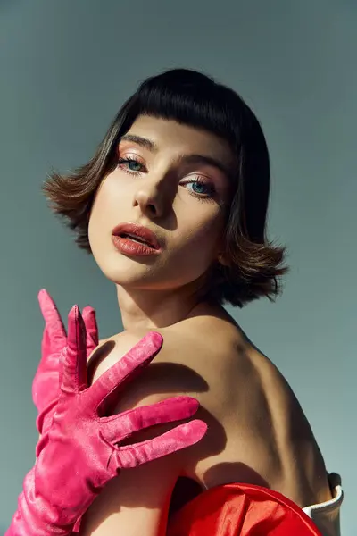 A stunning young woman showcases her fashion in a bold red dress and vibrant gloves. — Stock Photo