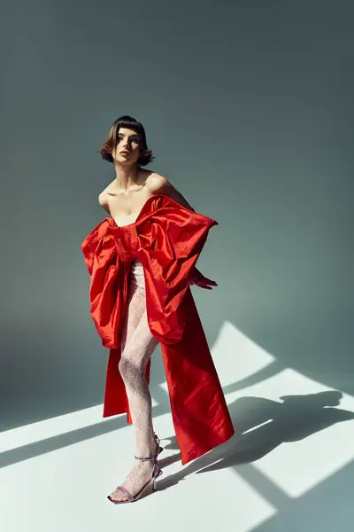 A stylish young woman showcases a bold red dress with a large bow. — Stock Photo