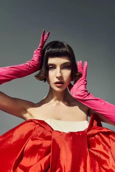 A stylish young woman poses gracefully in a striking red dress with a dramatic bow. — Stock Photo