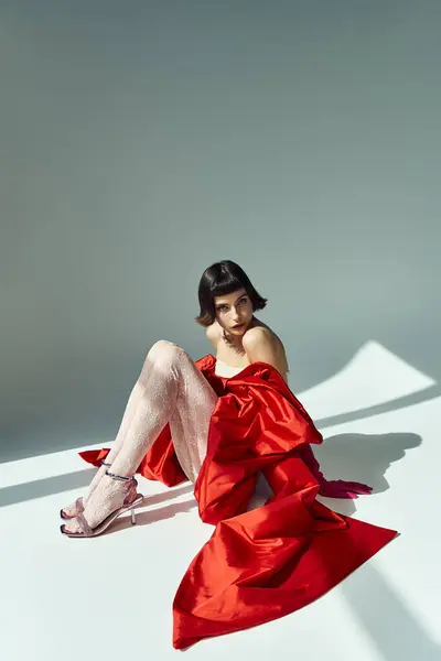 A beautiful young woman styled elegantly in a vibrant red dress with oversized bow. — Stock Photo