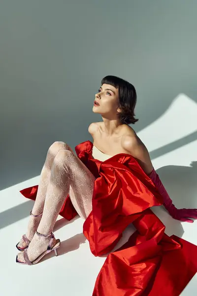 A stunning young woman captivates with her red dress and striking pose. — Stock Photo