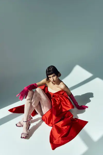 A stylish young woman showcases her fashionable red dress in an artistic pose. — Stock Photo