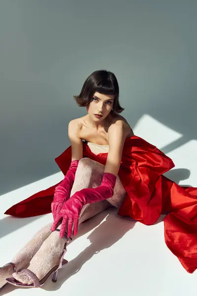 Une femme élégante aux cheveux courts se détend dans un ensemble rouge frappant avec des gants. — Photo de stock