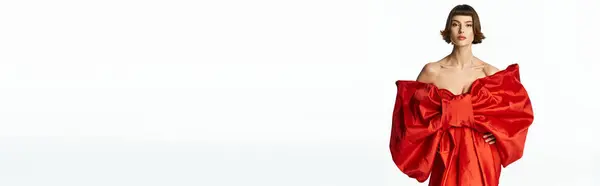 A fashionable young woman showcases her striking red dress adorned with a large bow. — Stock Photo