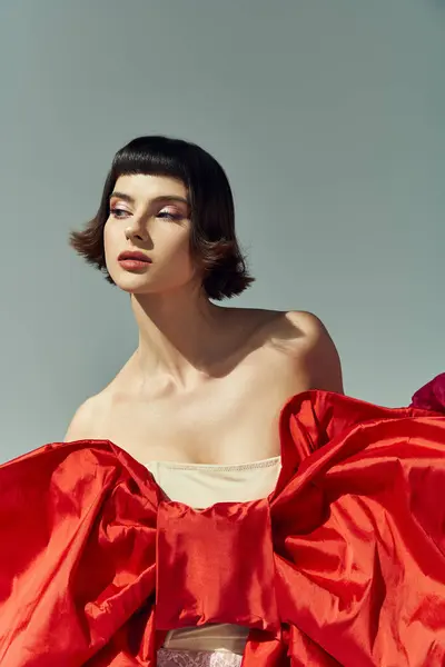 Youthful beauty shines in a red dress with a bold bow against a soft backdrop. — Stock Photo