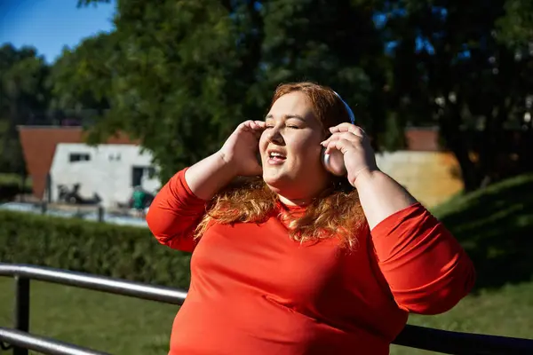 A plus size woman relaxes and exercises outdoors, immersed in her music. — Stock Photo