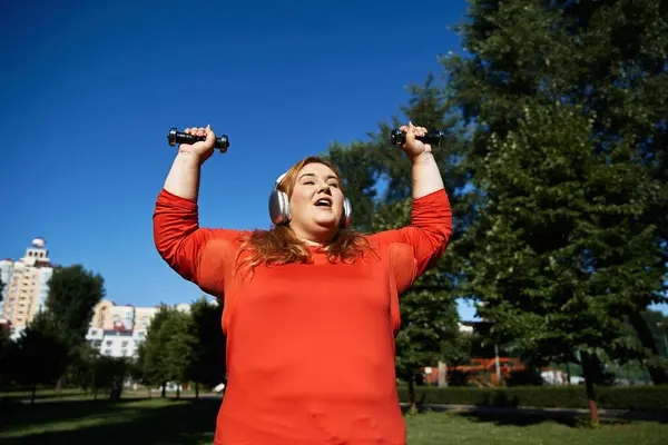 Energetico plus size donna solleva manubri mentre si gode una giornata di sole all'aperto. — Foto stock
