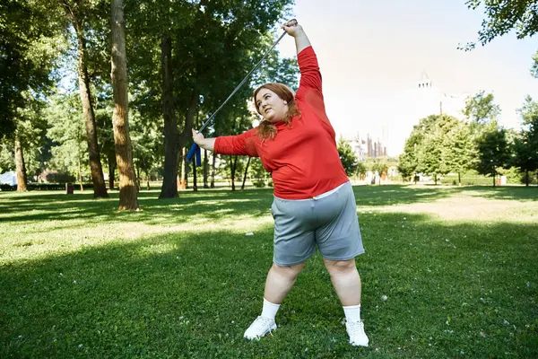 Una donna fiduciosa si impegna in esercizio, allungando il suo corpo in un parco vibrante. — Foto stock