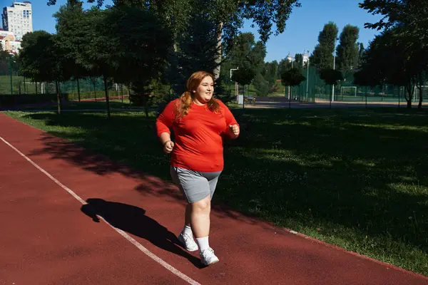 Une femme joyeuse fait des exercices dans le parc, profitant de sa course en plein air. — Photo de stock