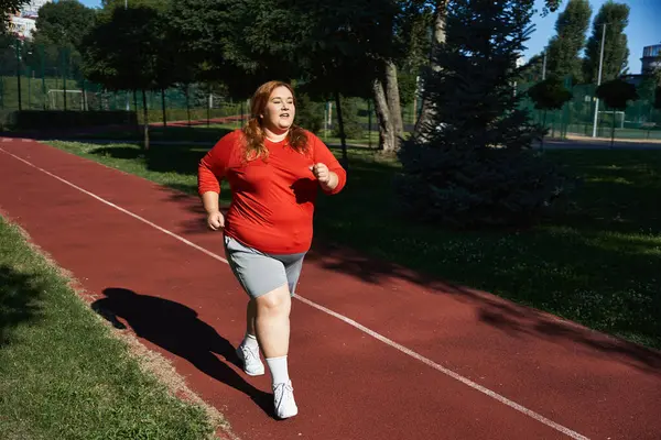 Una donna gioiosa si allena all'aperto, facendo jogging lungo un sentiero panoramico nel parco. — Foto stock