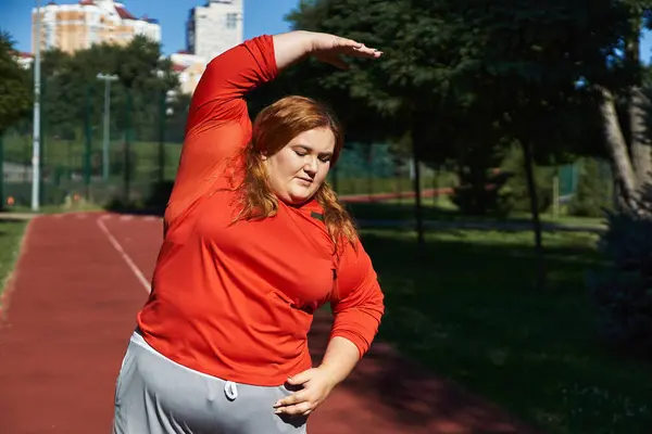 Женщина plus size выполняет упражнения на растяжку на открытом воздухе в парке. — стоковое фото