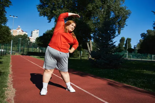 Una vivace donna plus size gode di stretching come lei esercita all'aperto. — Foto stock