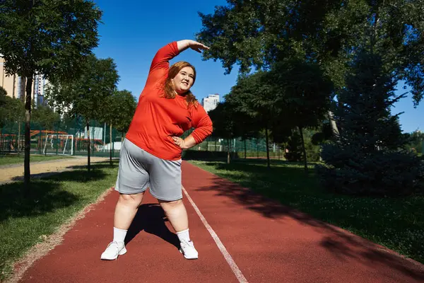 Una mujer alegre se estira mientras hace ejercicio al aire libre en un día vibrante. — Stock Photo