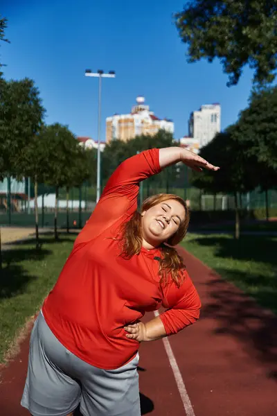 A joyful woman stretches in a park, embracing the morning sun. — Stock Photo