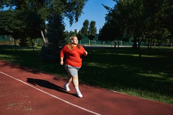 A plus size woman jogs with enthusiasm along a park path. — Stock Photo